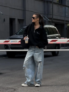 Urban street style look featuring black half-zip sweatshirt and distressed wide-leg jeans