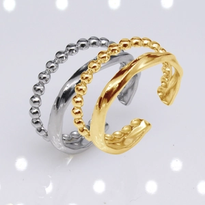 Close-up of three adjustable stackable rings in gold and silver finish with wave textures