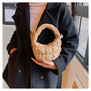 Close-up of beige quilted bubble bag carried by a model wearing a dark cashmere coat