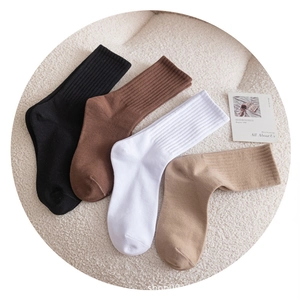 Socks en coton en noir, marron, blanc et beige disposées sur un tissu en peluche beige