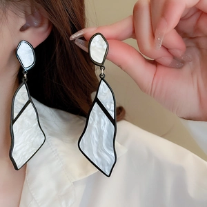 Detail of geometric acrylic earrings with black alloy frame and white marble texture