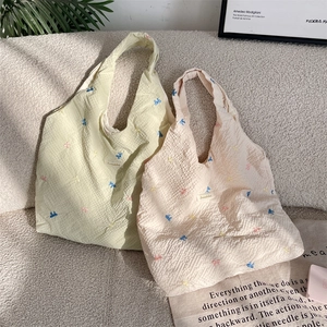 Détail de motifs papillons brodés sur des sacs cabas en tissu crépon gaufré