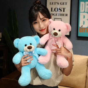 Plush teddy bear dolls in pink and blue colors held by a model in a cozy setting