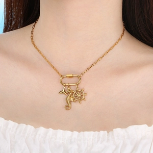 Détail de collier doré avec pendentifs hippocampe, gouvernail et queue de poisson