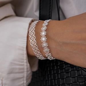 Close-up of hollow clover and daisy pattern silver cuff bracelet with metallic finish