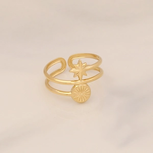 Detail of gold double-layer star and sunburst pendant ring on marble background