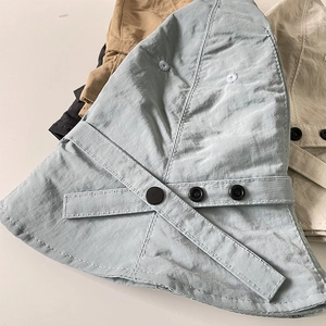 Close-up of lightweight nylon bucket hats with decorative cross straps and snap details