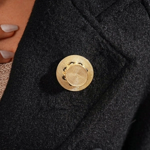 Macro shot of gold straw hat brooch with woven texture on a black wool blazer lapel