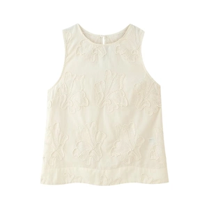 Gros plan détaillé sur la broderie florale texturée de ce gilet sans manches blanc crème