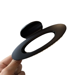 Große matt-schwarze Haarspange mit hohlem Oval-Design, von Hand vor weißem Hintergrund