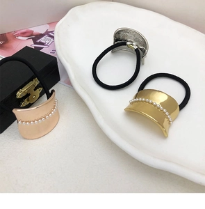 Close-up of three metal hair ties in gold silver and rose gold with tiny pearl accents
