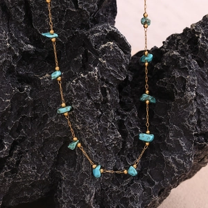 Macro detail of turquoise stone fragments and 18K gold plated beads on a delicate chain