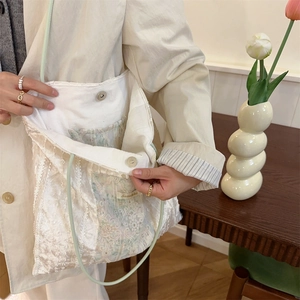 Detail view of the lace tote bag featuring its magnetic buckle and spacious white interior