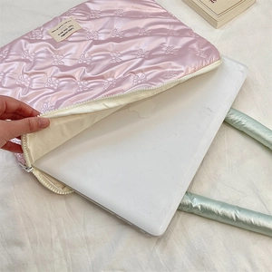 Detailed view of pink quilted laptop sleeve with bow texture and shockproof yellow lining