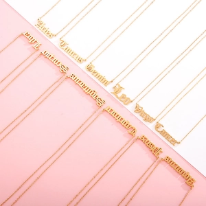 Detailed overhead view of 18k gold zodiac nameplate necklaces in gothic font style