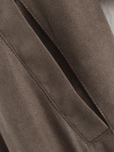 Detailed macro shot of the deep brown faux suede jacket pocket with premium stitching