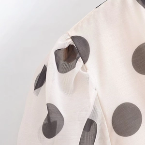 Détail de l'épaule bouffante et imprimé à pois sur tissu mousseline beige translucide