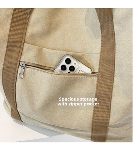Close-up of beige canvas tote bag showing the front zipper pocket for smartphone storage
