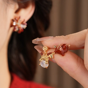 Detailed view of 18k gold plated winged horse earrings with red enamel and large zircon