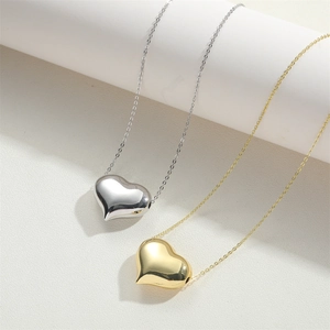 Dettaglio di ciondoli a cuore lucidi in oro e argento con catenine sottili