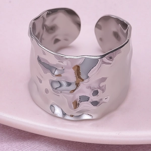 Detail of wide 304 stainless steel ring with hammered texture on a pink ceramic plate