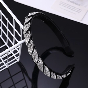 Detail of a black twisted headband with sparkling rhinestones on a reflective surface