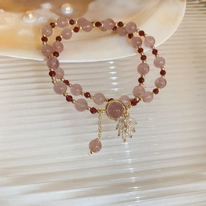 Close-up of double-layer beaded bracelet with pink crystals and rhinestone leaf charms