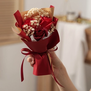 Close-up of mini red soap roses and baby's breath wrapped in red and gold paper