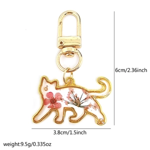Detailed view of cat keychain dimensions with real dried flowers and golden resin frame
