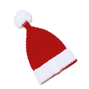 Close-up of red and white knitted Christmas hat with a fluffy pompom and ribbed cuff detail