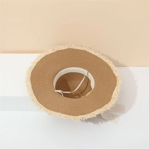 Detailed shot of straw sun hat with frayed fringe edges and delicate lace tie-on detail