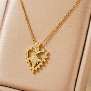 Golden heart pendant necklace with star zircon accent on a luxury jewelry box