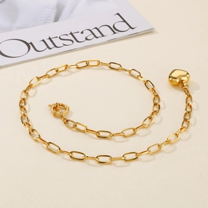 Gold chunky chain necklace with a heart pendant and spring clasp on a minimal background