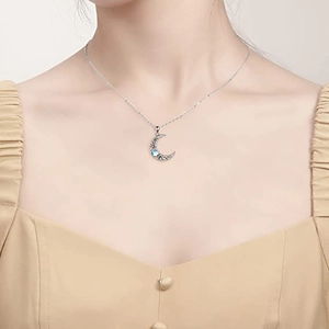 Detail of crescent moon pendant with blue gemstone on silver chain worn by a model