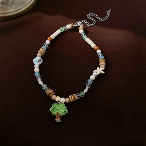 Detail of beaded necklace with ceramic tree and starfish charms on brown velvet
