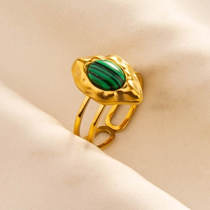 Detail of adjustable gold-plated ring with oval green malachite stone on textured fabric