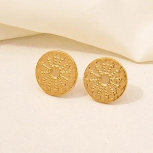 Macro detail of golden sunburst earrings with beaded texture on soft satin fabric