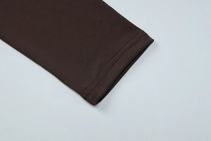 Detailed close-up of double-stitched cuffs on dark brown pleated long sleeve dress
