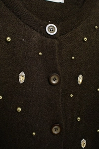 Detail of dark brown knit cardigan with golden beads and oval crystal embellishments