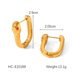Détail des boucles d'oreilles serpent dorées 18k avec yeux rouges et texture écailles