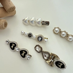 Detail of assorted vintage pearl and rhinestone duckbill hair clips in gold finish