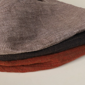 Linen bucket hats in grey, brown and rust red stacked to show fine knit texture