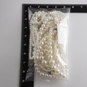 Macro view of imitation pearl body chain with multiple sizes in brand packaging