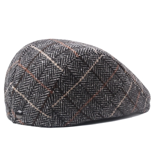 Detail of wool herringbone newsboy cap featuring orange plaid and metal buckle