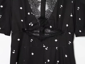 Dettaglio di un abito nero con delicato scollo a V in pizzo e piccole stampe floreali