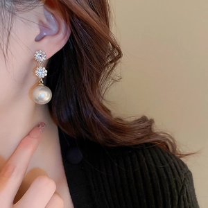 Gros plan sur les boucles d'oreilles fleur dorées avec cristaux et perles blanches