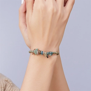 Nahaufnahme des handgefertigten Armbands mit Naturkristallsteinen und goldenen Perlen