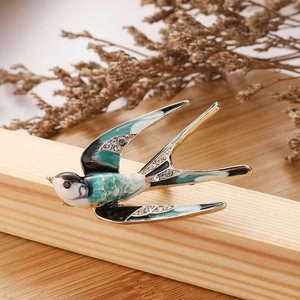 Exquisite enamel swallow brooch with sparkling crystals on natural wood stand