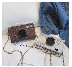 Detail of silver and brown sequined camera-shaped bags with chain straps on a lifestyle backdrop