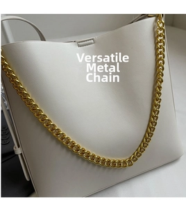 Detailed close-up of premium cream leather bag with bold gold metal chain strap